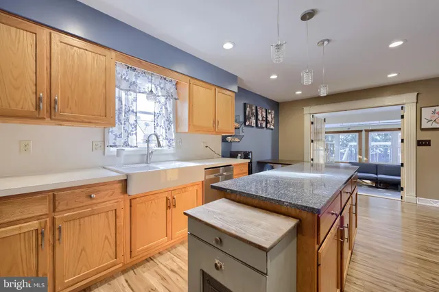 a kitchen with stainless steel appliances granite countertop a refrigerator a stove and a sink with wooden floor