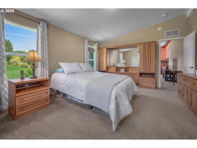 a bedroom with a bed table flowerpot and window