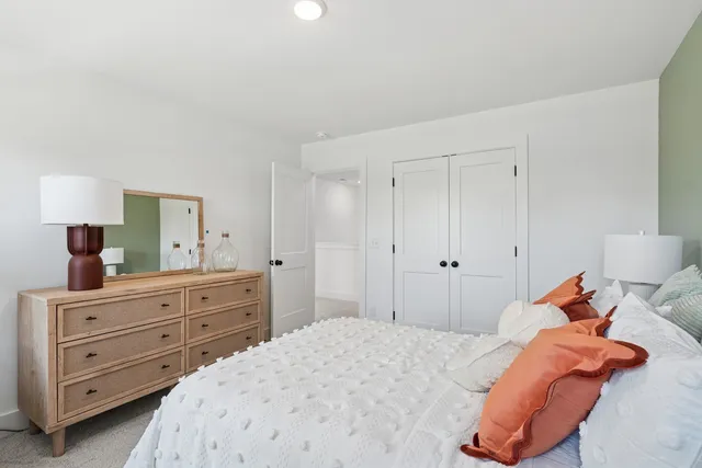 a bedroom with a bed and a lamp on dresser