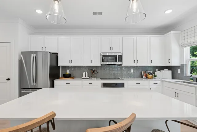 a kitchen with stainless steel appliances a refrigerator sink and white cabinets