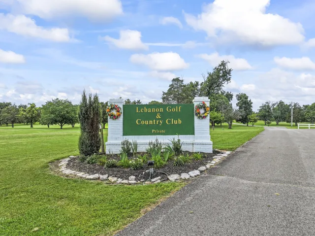 a sign board with grassy field in back