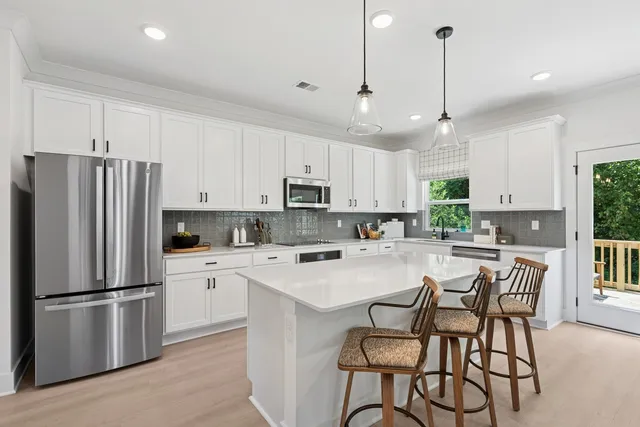 a kitchen with stainless steel appliances a refrigerator a stove a sink and white cabinets