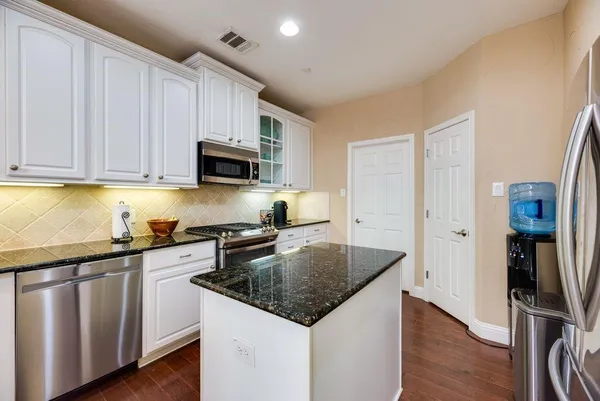 a kitchen with granite countertop a sink and a stove top oven with wooden floor