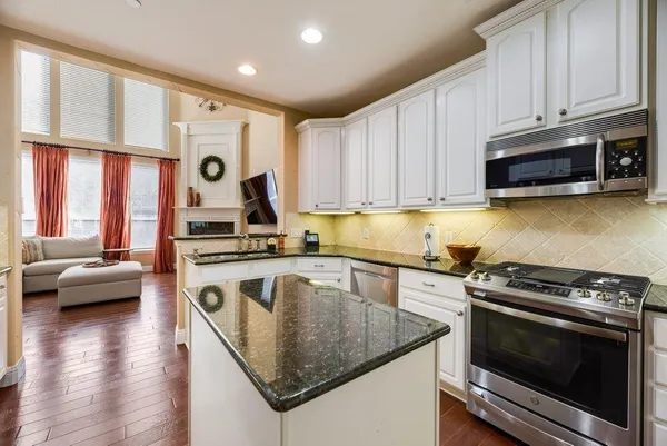 a kitchen with stainless steel appliances granite countertop a stove a sink and a microwave