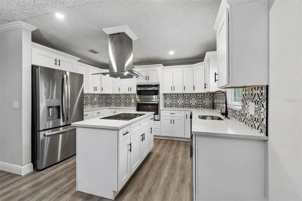 a kitchen with a sink a refrigerator a stove and white cabinets
