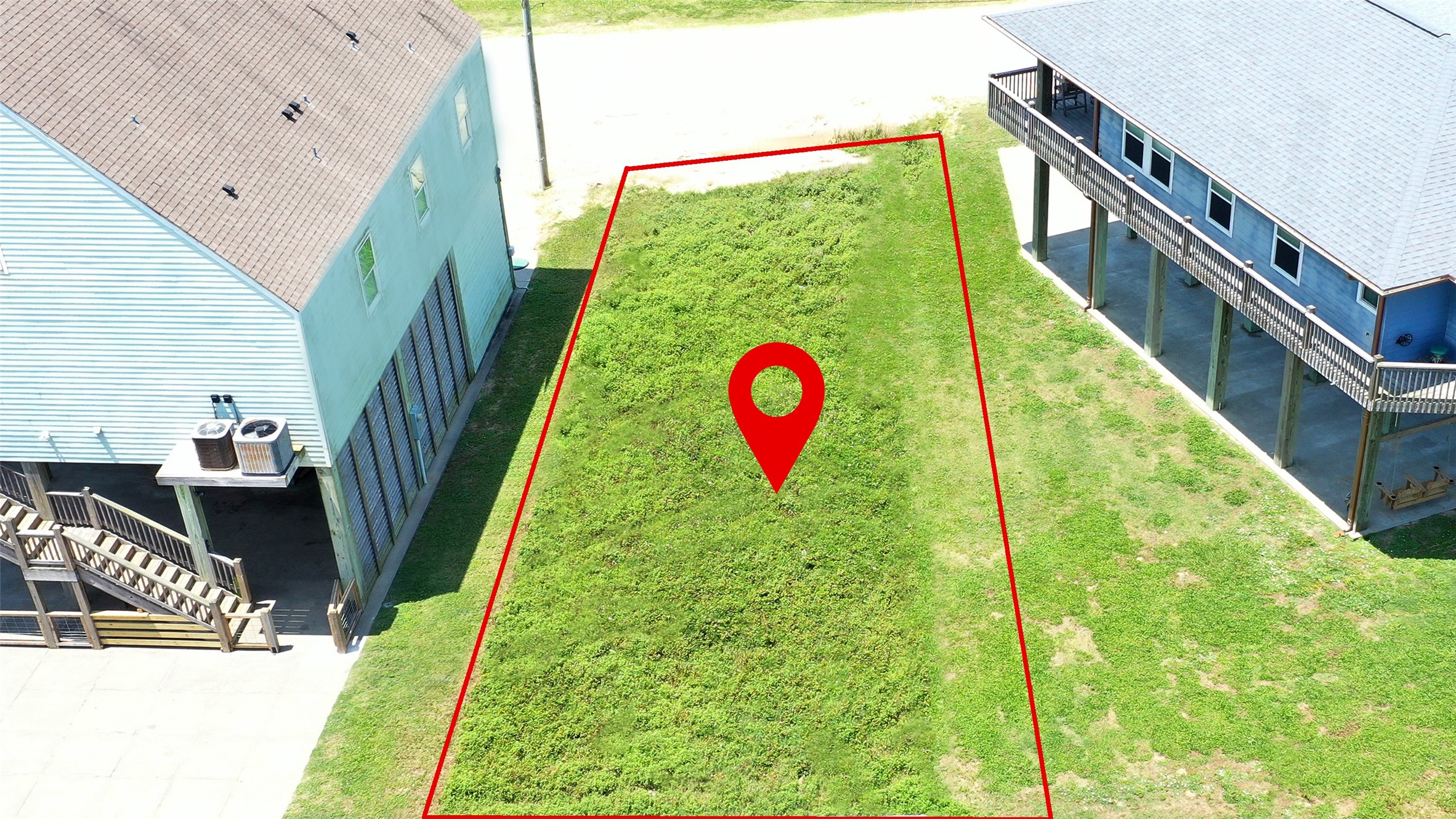 0 Crystal Beach Road Crystal Beach, TX 77650 - Photo 4 of 18 This photo shows a vacant lot outlined in red, situated between two elevated houses. The plot is grassy and flat, offering a clear space for potential construction. Ideal for buyers looking to build in a residential area.