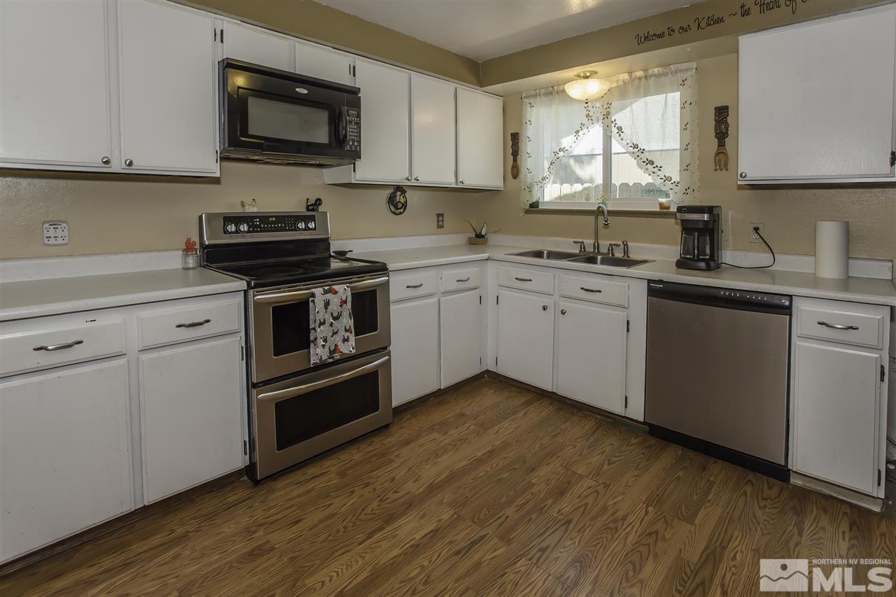 4425 Leche Way Reno, NV 89502 - Photo 10 of 25 a kitchen with stainless steel appliances granite countertop a sink a stove a microwave and wooden cabinets