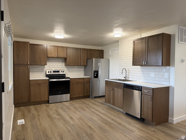 895 East Arrowhead Lane Murray, UT 84107 - Photo 1 of 12 Kitchen featuring stainless steel appliances, wood-finish cabinetry, white subway tile backsplash, and light countertops
