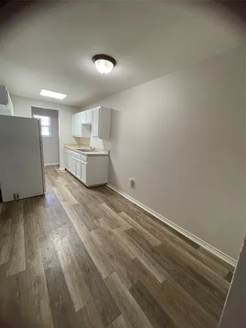 a view of a kitchen with white cabinets and wooden floor