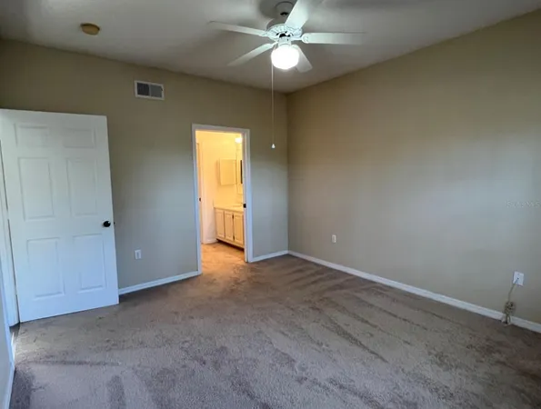 an empty room with closet and a chandelier fan