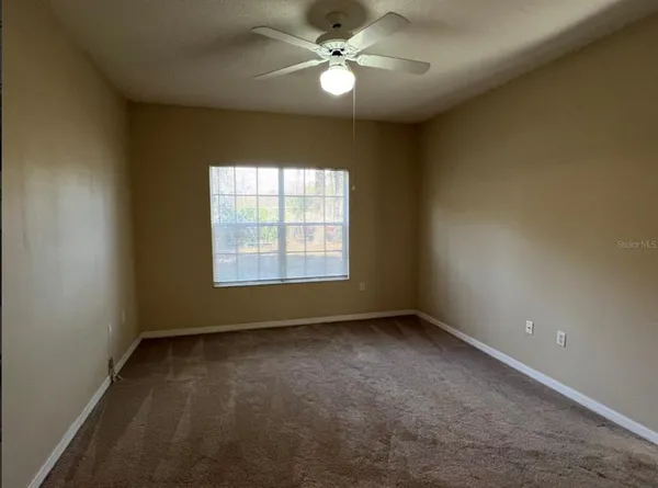 an empty room with a window and a fan