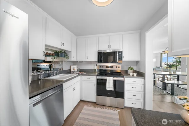a kitchen with stainless steel appliances granite countertop a sink stove refrigerator and cabinets