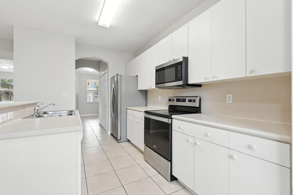 24055 Southwest 109th Court Homestead, FL 33032 - Photo 17 of 42 a kitchen with granite countertop a sink a stove top oven and cabinetry