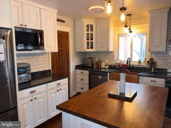 a kitchen with stainless steel appliances kitchen island granite countertop a sink dishwasher stove top oven and refrigerator with wooden floor