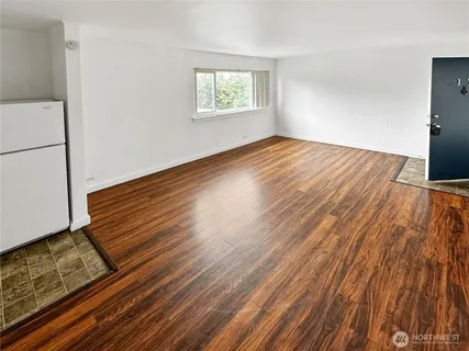 a view of an empty room with wooden floor and a window