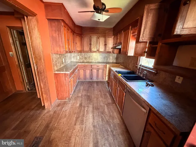 a kitchen with stainless steel appliances granite countertop a refrigerator a sink dishwasher a stove and white countertops with wooden floor