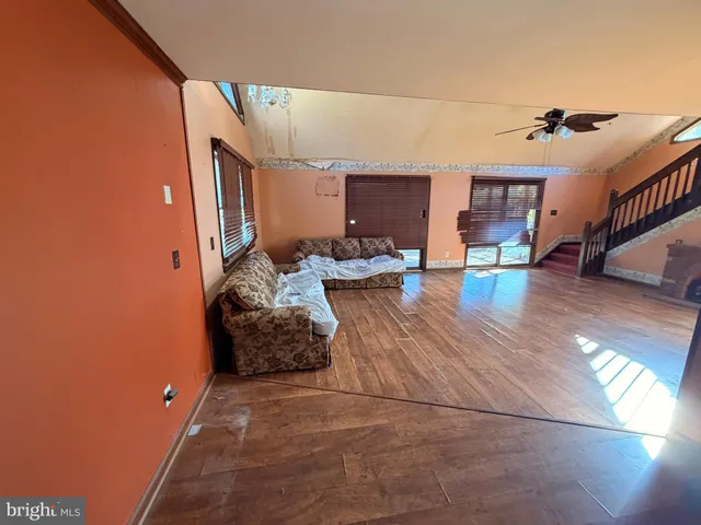 a living room with couches bookshelf and wooden floor
