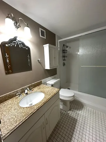 a bathroom with a granite countertop sink toilet and shower