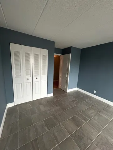 a view of an empty room with closet and a bathroom