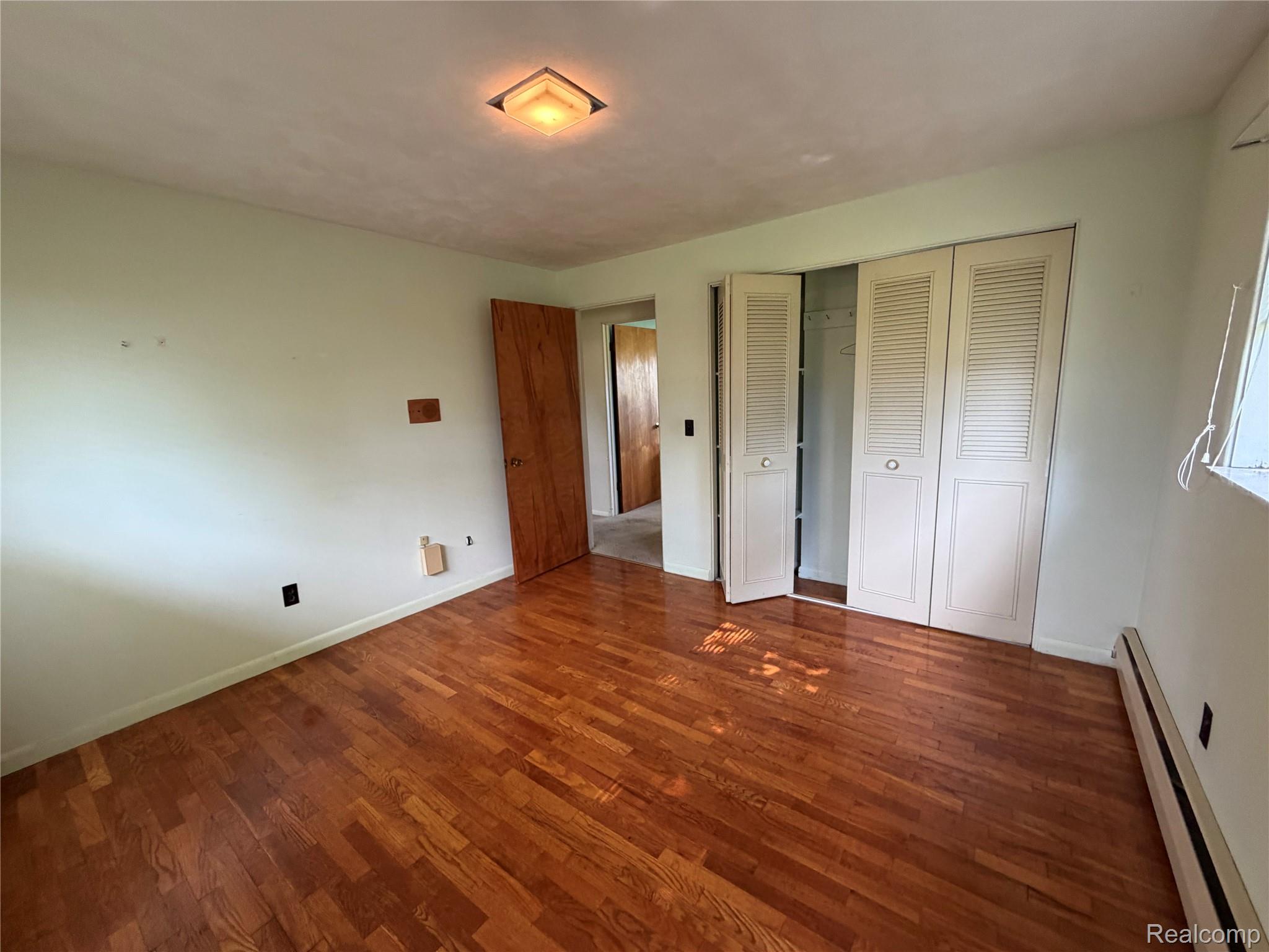 8886 East Burnside Road Brown City, MI 48416 - Photo 14 of 22 Hardwood flooring throughout featuring white louvered bifold closet doors and a flush-mount ceiling light fixture