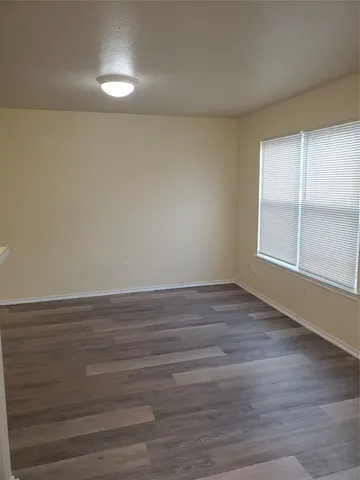an empty room with wooden floor cabinet and windows