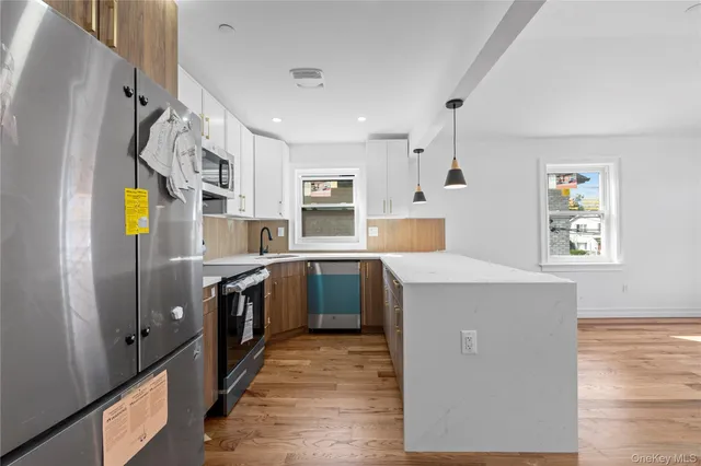 a kitchen with kitchen island wooden floors appliances and cabinets