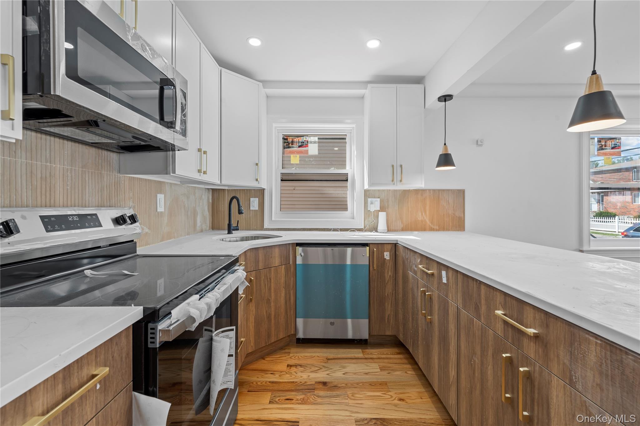 258-14 147th Road Queens, NY 11422 - Photo 5 of 22 Kitchen with stainless steel appliances, light wood finished floors, white cabinetry, tasteful backsplash, and brown cabinetry