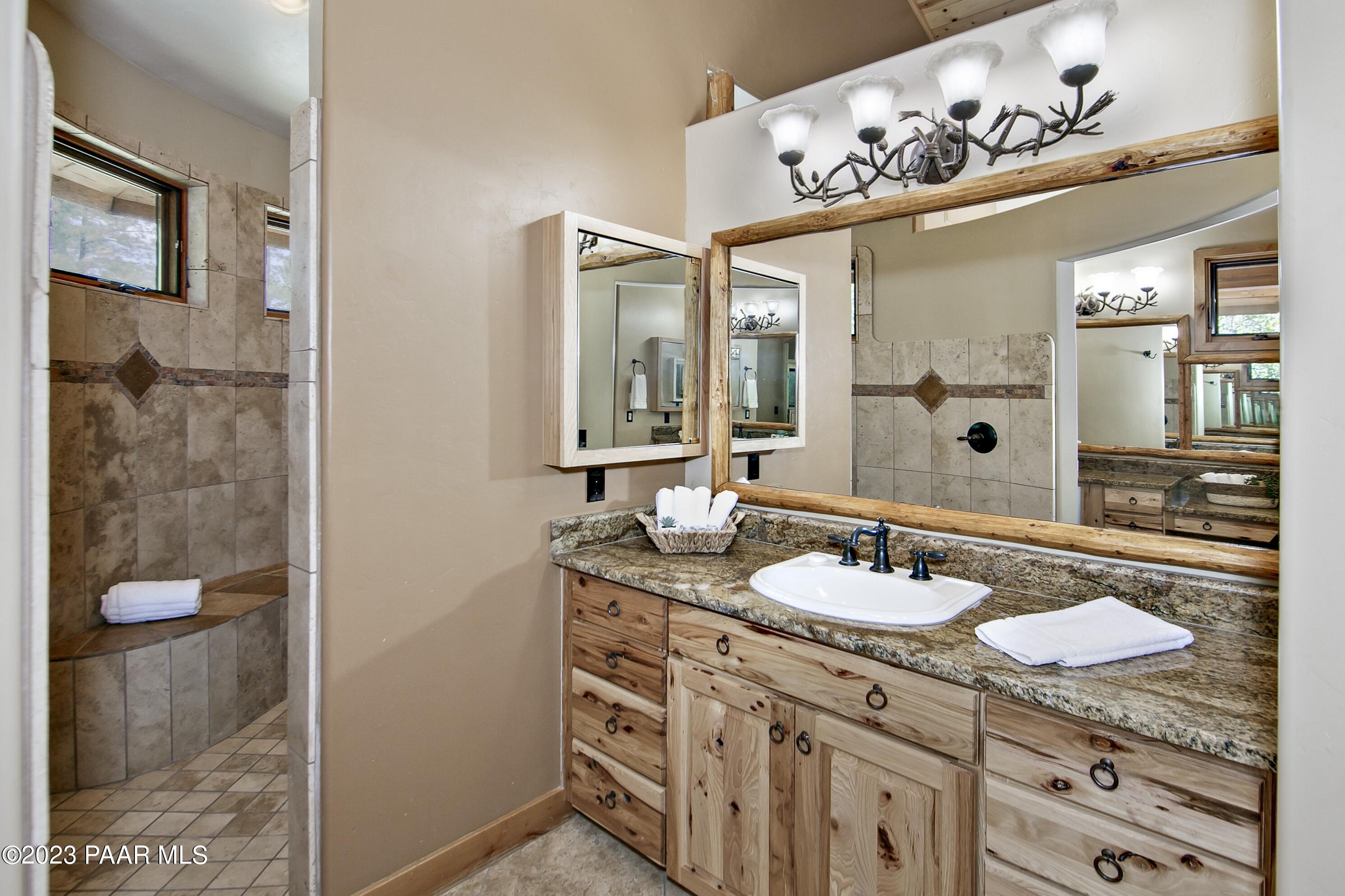 5140 East Charcoal Kiln Road Prescott, AZ 86303 - Photo 26 of 77 a bathroom with a granite countertop sink a mirror and shower