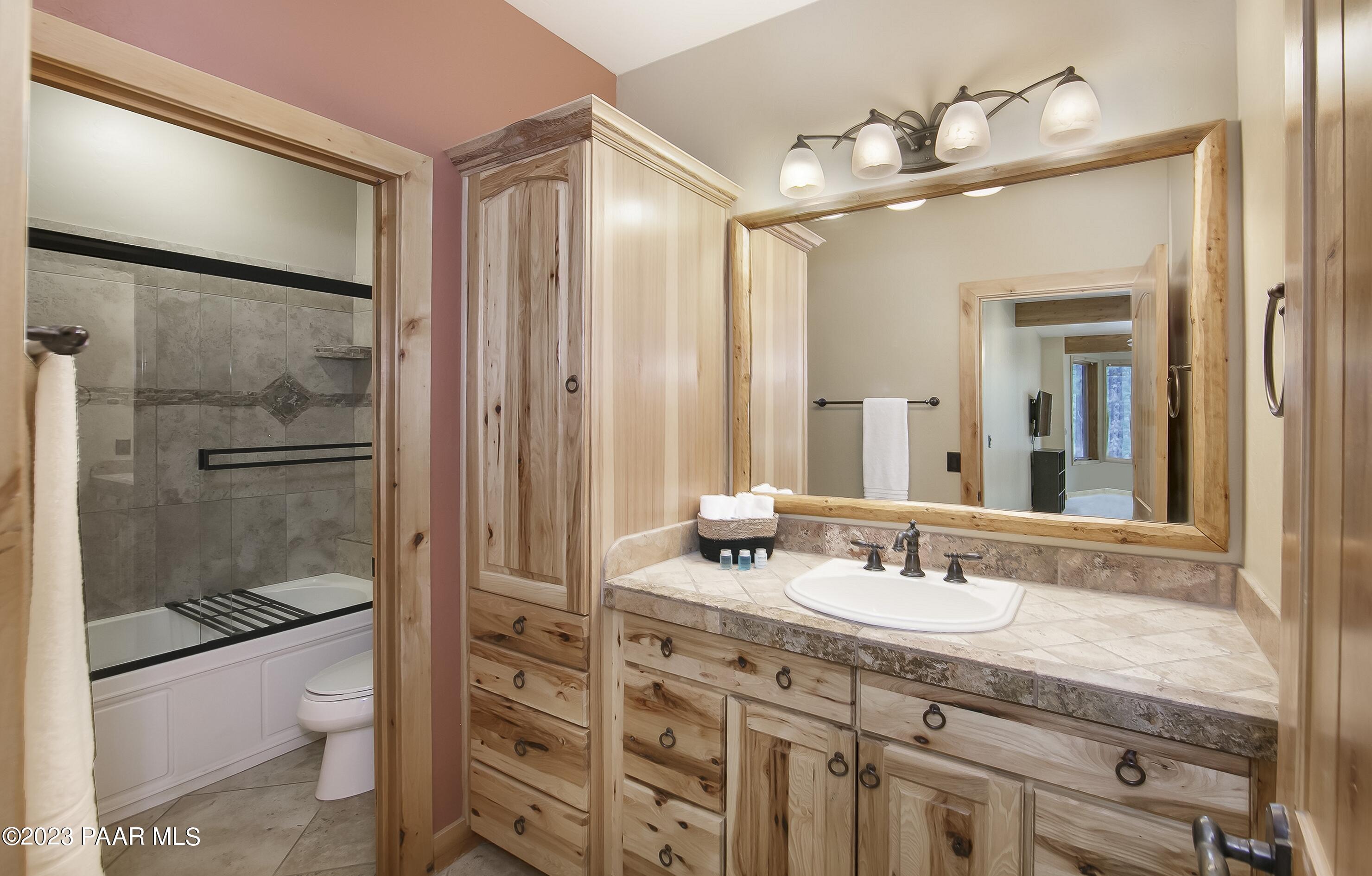 5140 East Charcoal Kiln Road Prescott, AZ 86303 - Photo 39 of 77 a bathroom with a granite countertop sink a toilet a mirror and shower