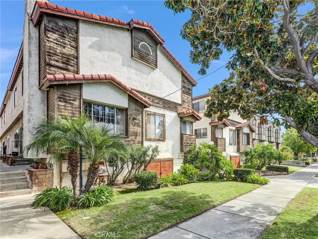 a front view of a house with a yard and potted plants