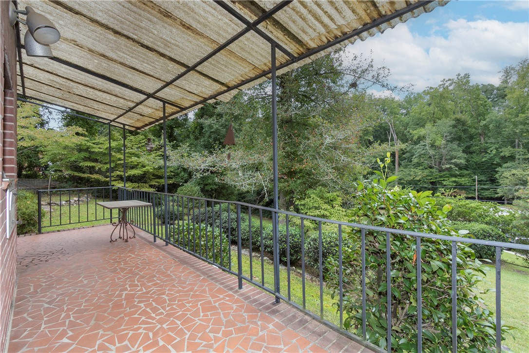 118 Blair Road Belton, SC 29627 - Photo 41 of 49 A covered porch displays tiled flooring and metal railings overlooking a wooded backyard landscape.