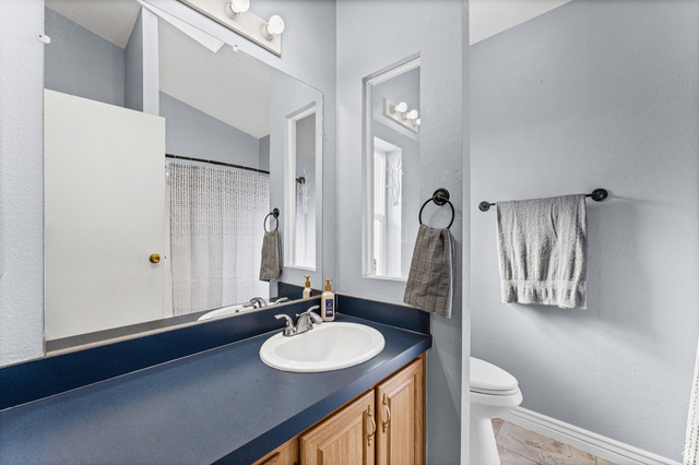 312 Harriger Way Layton, UT 84041 - Photo 25 of 36 Vanity with a white oval sink and chrome faucet, set into a dark blue countertop