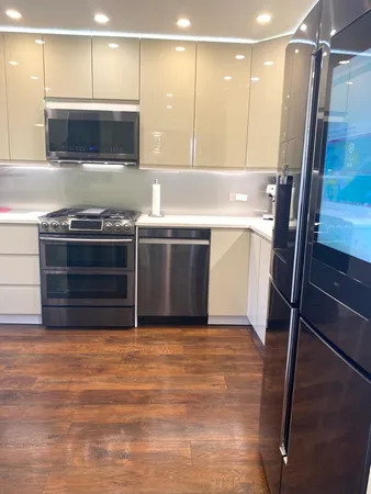 a view of kitchen with stainless steel appliances wooden floor and staircase