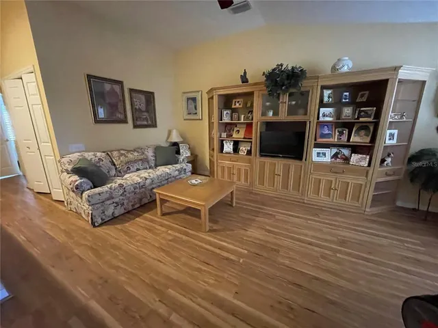 a living room with furniture a book shelf and wooden floor