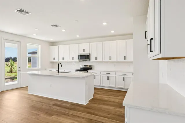 a large kitchen with stainless steel appliances granite countertop a lot of counter space and wooden floors
