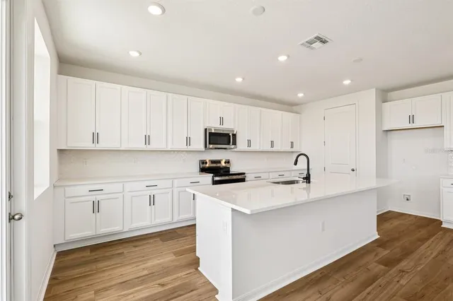 a kitchen with granite countertop white cabinets and stainless steel appliances