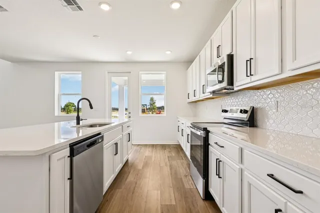 a kitchen with white cabinets appliances and a sink
