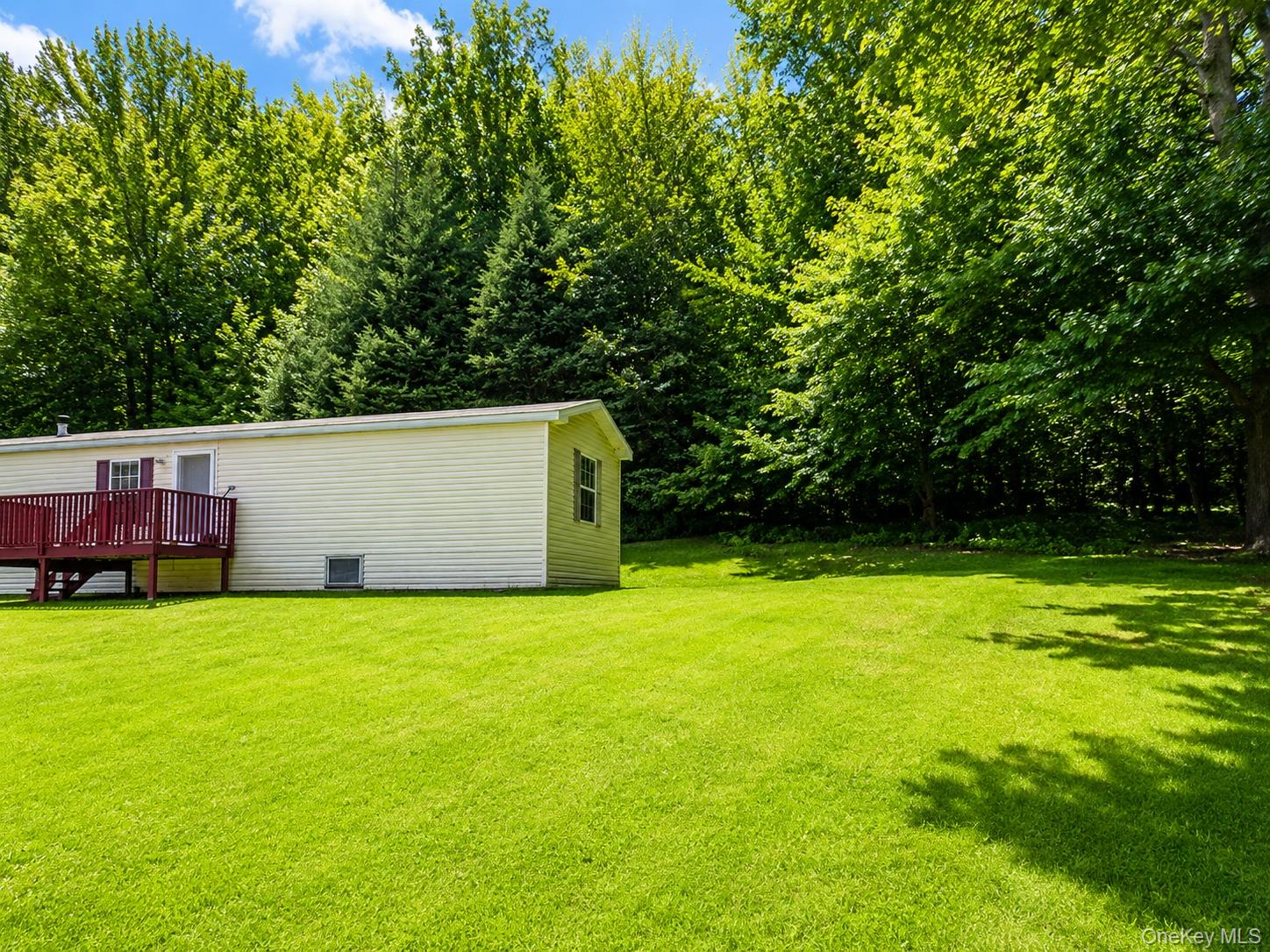182-184 Mutton Hill Road Neversink, NY 12765 - Photo 20 of 36 Expansive lawn area with a light-colored siding structure featuring a red-stained wood deck, steps, and railing