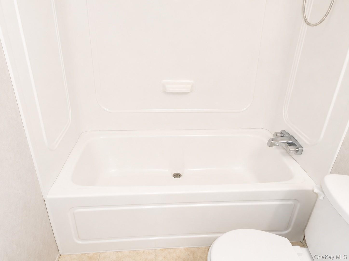 182-184 Mutton Hill Road Neversink, NY 12765 - Photo 33 of 36 White bathtub with integrated shower surround, chrome fixtures, and a textured floor tile