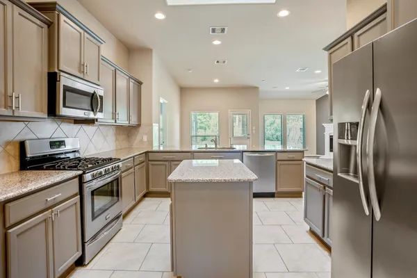 a kitchen with stainless steel appliances granite countertop a sink a stove and a refrigerator
