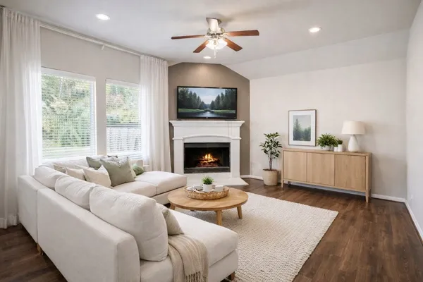 a view of a livingroom with a fireplace a ceiling fan and wooden floor