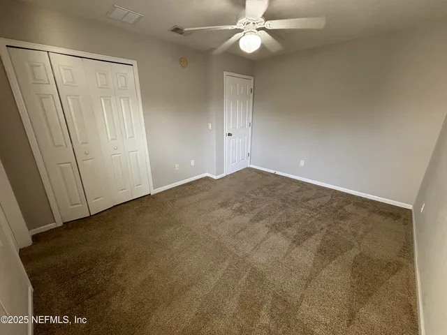 an empty room with a ceiling fan and a window