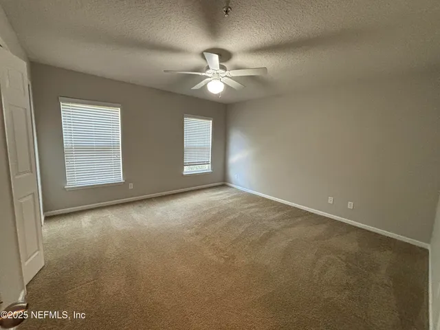 an empty room with closet and a ceiling fan