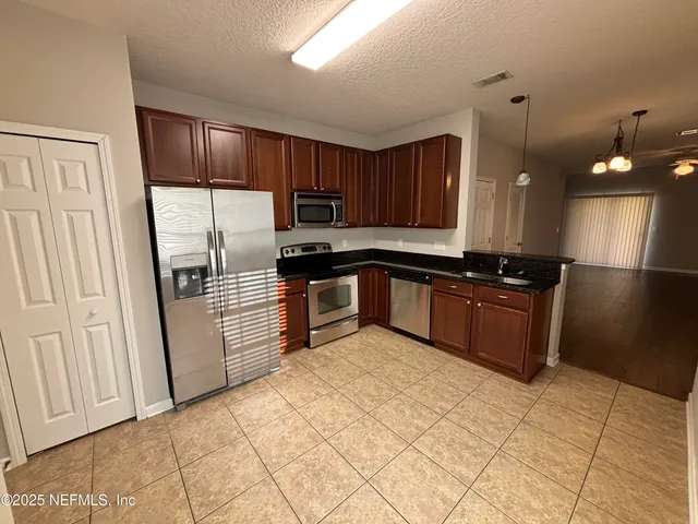a kitchen with granite countertop a refrigerator a sink and wooden cabinets