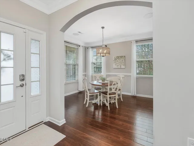 a dining room with wooden floor a chandelier a glass table and chairs