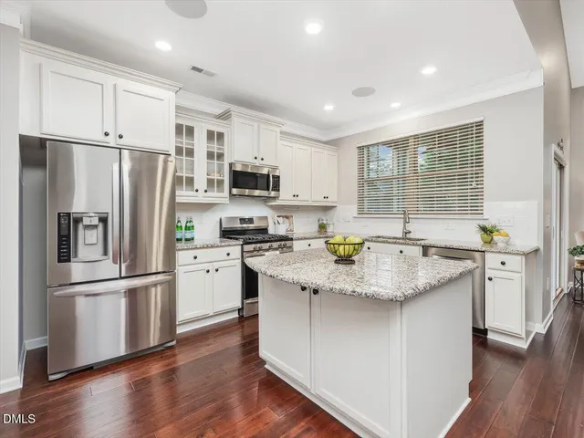 a kitchen with stainless steel appliances granite countertop a refrigerator a sink dishwasher a stove and a refrigerator with wooden floor