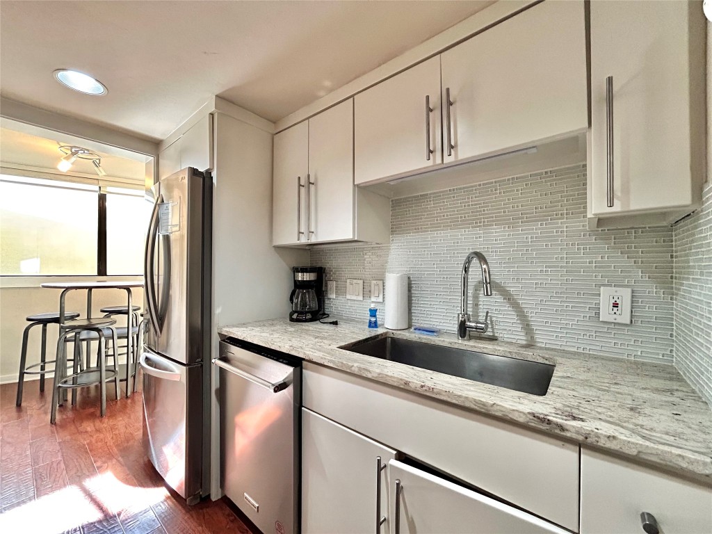1106 West 6th Street, Unit 205 Austin, TX 78703 - Photo 9 of 27 Kitchen featuring stainless steel appliances, light stone counters, backsplash, dark wood-style flooring, and recessed lighting
