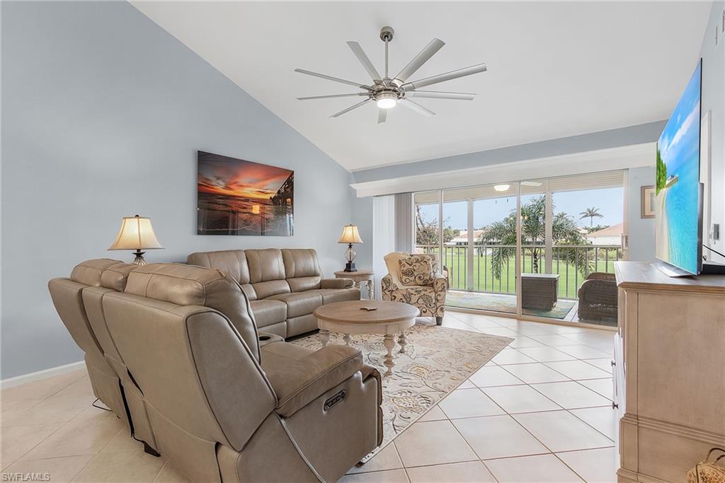 6780 Dennis Circle, Unit M206 Naples, FL 34104 - Photo 18 of 26 a living room with furniture a flat screen tv and a large window