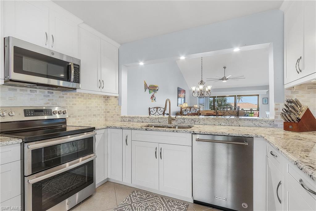 6780 Dennis Circle, Unit M206 Naples, FL 34104 - Photo 2 of 26 a kitchen with stainless steel appliances granite countertop a stove top oven microwave and cabinets