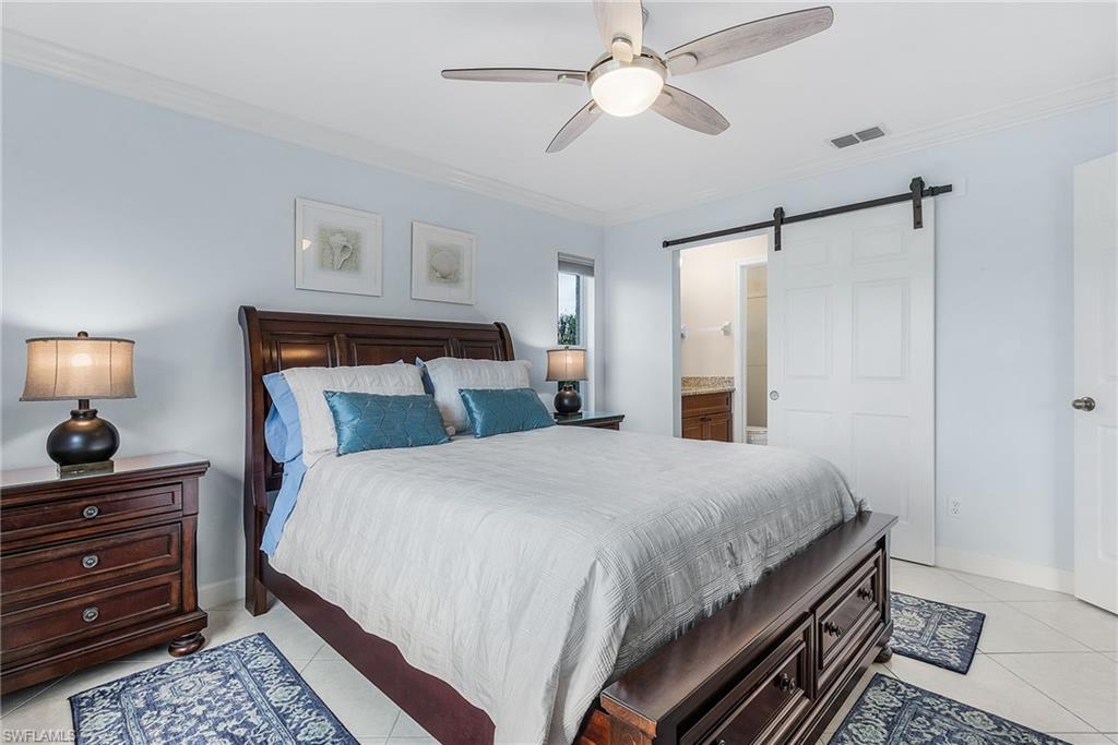 6780 Dennis Circle, Unit M206 Naples, FL 34104 - Photo 22 of 26 a bedroom with bed and a chandelier